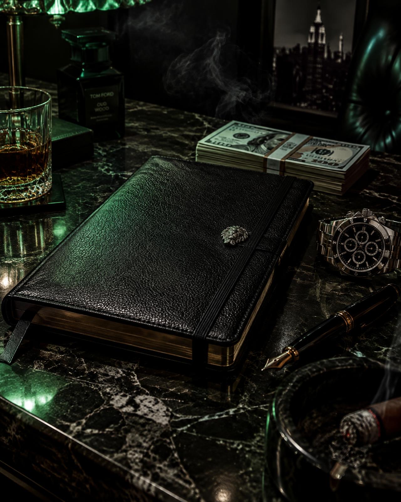 A black leather journal on a marble desk beside a luxury watch and stacked cash